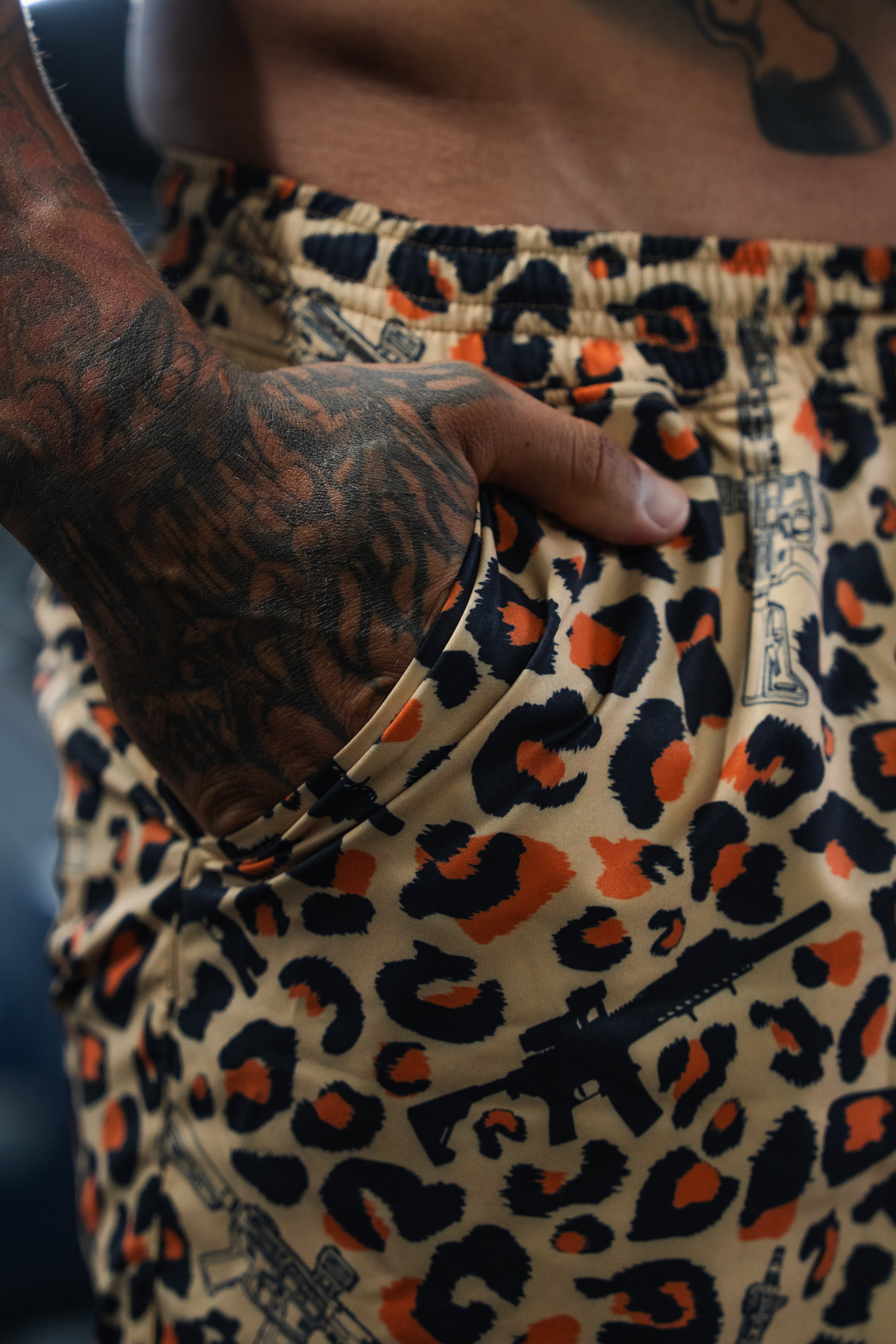 Person wearing a leopard print shirt with visible tattoos on arm